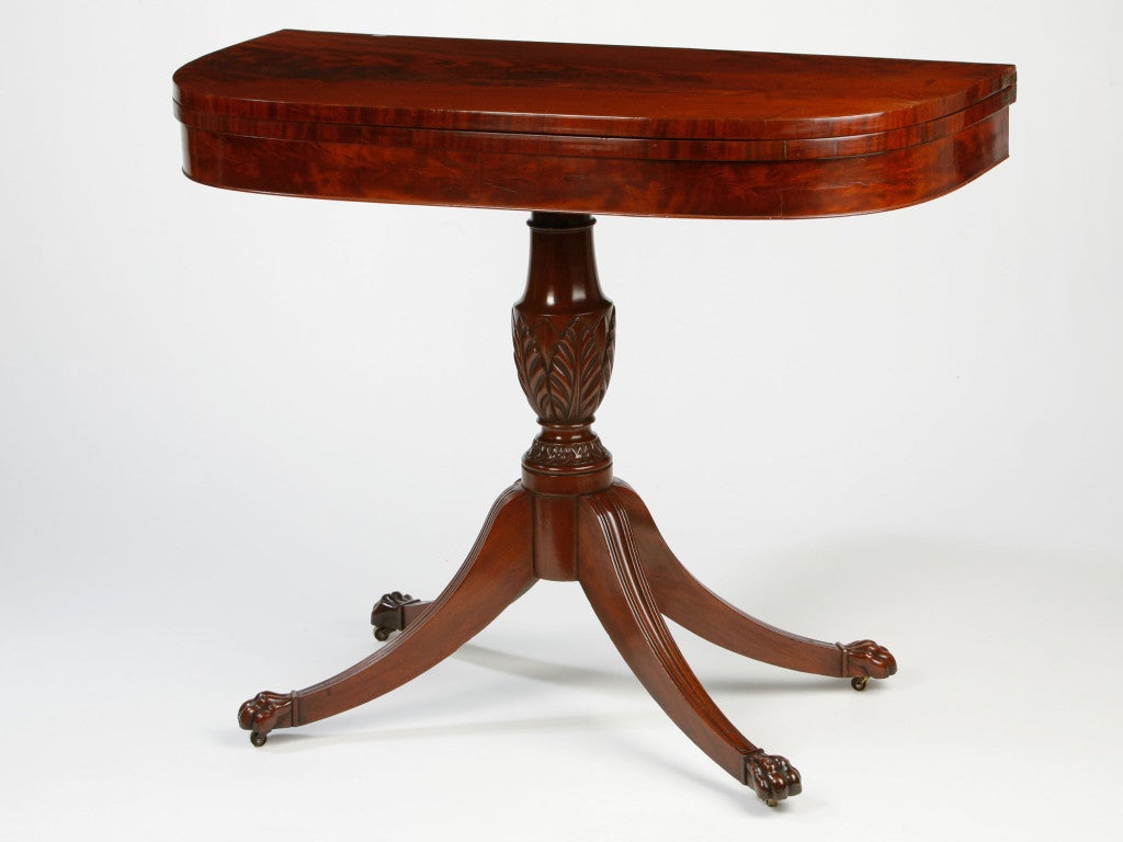 Fine quality D shaped card table with a carved urn shaped pedestal<br />
supported on down swept legs ending in animal paw feet. In the<br />
maner of Duncan Phyfe or one of his contemporaries.