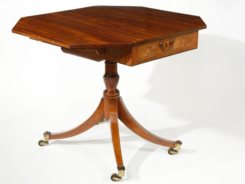 English Regency mahogany pembroke table having drop leaves with 

canted ends, one drawer, supported on a urn shaped pedestal with

downswept legs ending in brass casters, with a warm mellow patina.
