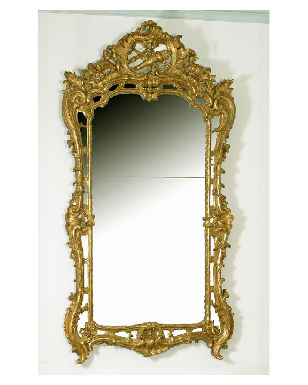 French Louis XV Gilt Mirror, The shaped crest carved with a bow<br />
crossed with a quiver of arrows, the shaped frame carved with<br />
flowers, foliage and scrolls.