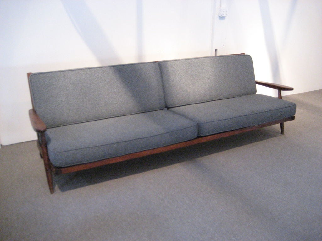This extra-long sofa with arms is in the classic Spindle-back form. It was commissioned for a convent and has the original wool upholstery!