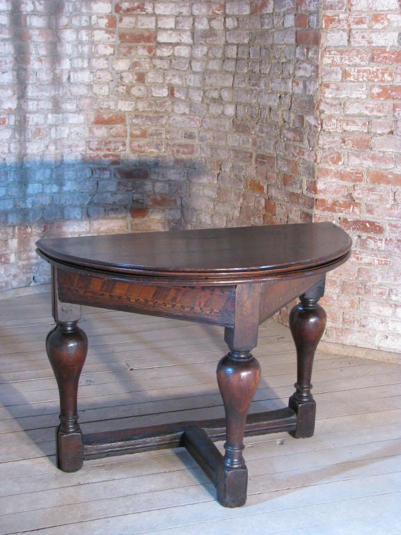 Flip top table, transforms from demi-lune console table to round center table.Beautifully shaped legs, the frieze decorated with geometric inlay, wonderful patina.
