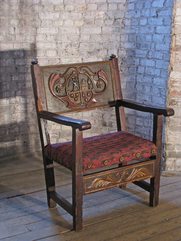 Rare and very special Spanish armchair, the back featuring a prominent coat of arms carved and with painted accents, conforming front stretcher.
Our pieces are left in lived-in condition, pending our custom conservation and polish to