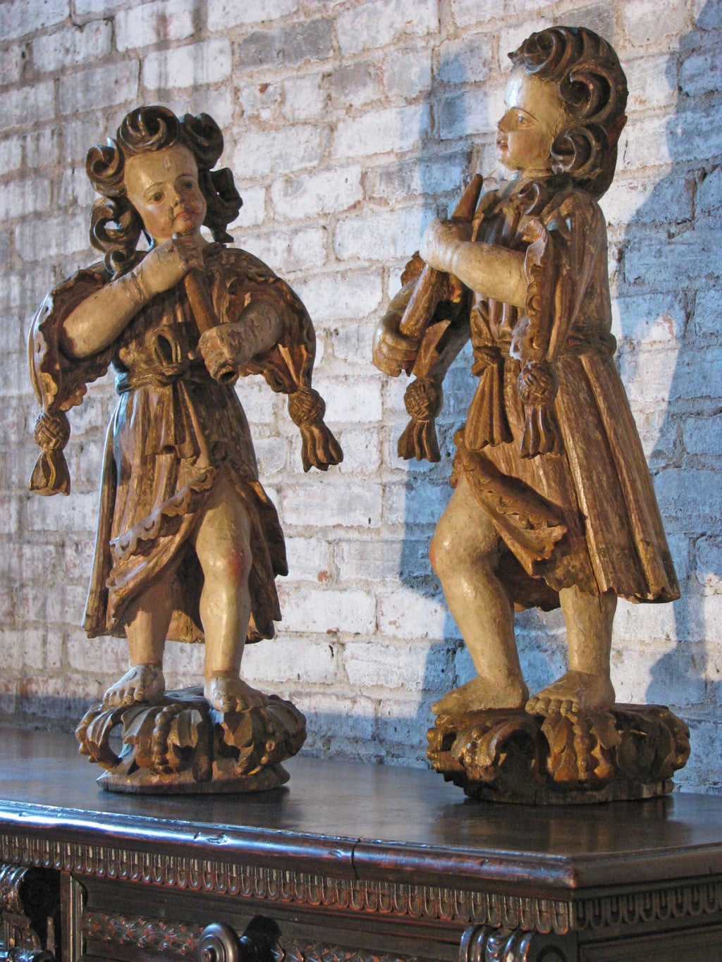 Charming and rare pair of carved wood and polychrome figures of joyous youths playing instruments.

