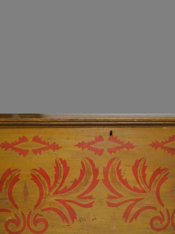 With yellow paint all over, the hinged lid with molded edge, the top and sides with red stencil decoration, raised on a molded base on short turned legs.<br />
<br />
This blanket chest features construction elements and materials characteristic