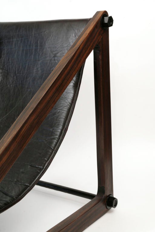 Phenomenal Brazilian sling chair circa mid 1960's. Features thick solid rosewood angular frame with black leather sling and nicely patinated hardware.