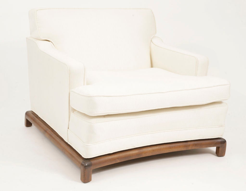 Chair and a half and ottoman circa mid 1950's. Features curved walnut base that circumvents the entire chair. Done in an elegant off white textured fabric. Price is for chair and ottoman.