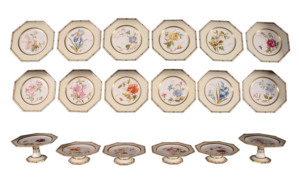 A Wedgewood octagonal shaped dessert service with gilded rims and pale yellow ground surrounding portraits of different flowers including roses and irises. Comprised of twelve plates and six footed compotes (two taller, and four shorter).