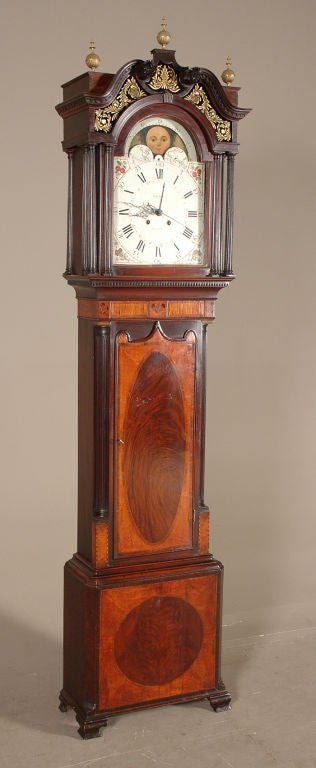 A tall case clock by Edward Bertles, Liverpool. With a moonphase dial, sweep second hand and date hand. The swan neck pediment terminates in finely carved rosettes. The case veneered with mahogany ovals surrounded by satinwood.