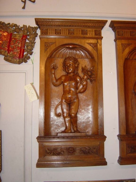 Four deeply carved  solid walnut panels with putti representing the Four Seasons. Each figure carrying various emblems 
