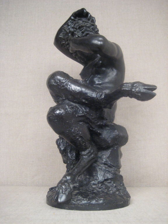 Wonderful bronze statue of satyr with hoof feet, possible Puck, seated on a rock and rubbing his eye.