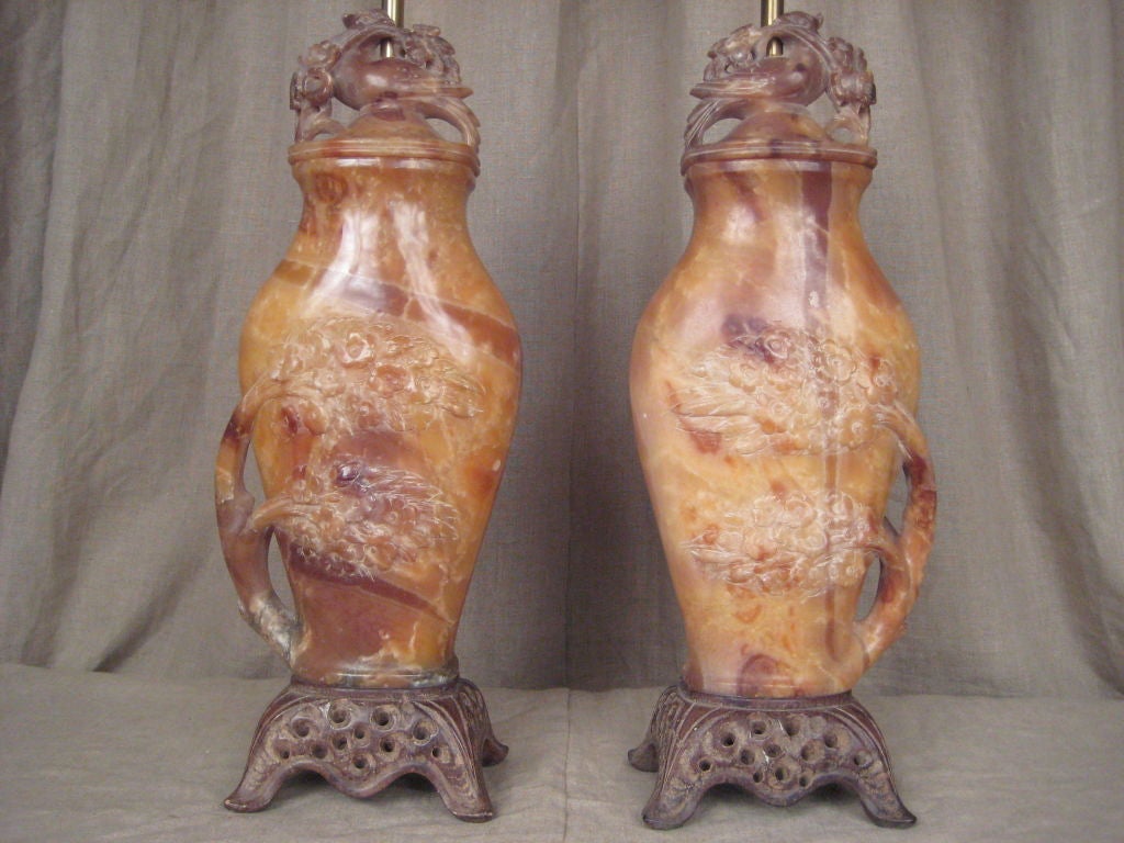 Pair of carved alabaster lamps with birds and leaves.