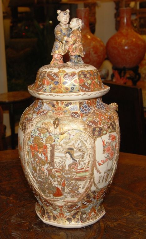 An intricately detailed Satsuma lidded urn. Hand applied decoration in relief on earthenware. Extensively patterned and multi-colored with gilded accents.