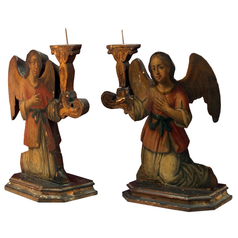 An unusual pair of candle-sticks, the cutout kneeling figures painted in the fashion of dummy boards