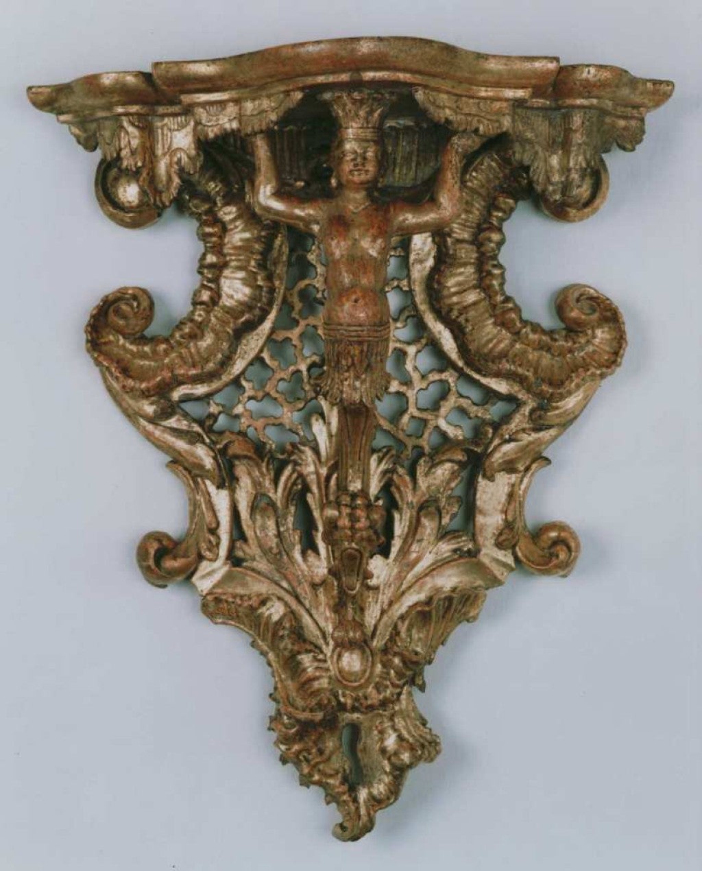 This highly sculptural console bracket is centered by a supporting herm figure in the guise of an American Indian with a crown of feathers. It was probably made as part of a series, each of which represented a continent, as was the fashion in the