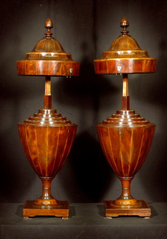Each with telescopic lid surmounted by a turned finial and opening to a fitted interior; raised on a socle base on bracket feet.
