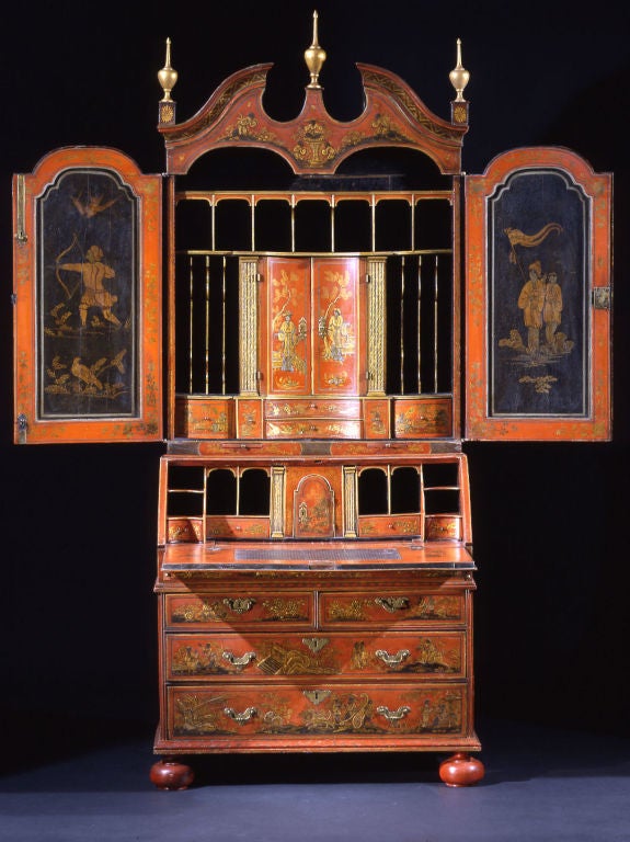 The broken arch pediment surmounted by gilt urn-shaped finials over a pair of mirror-front doors opening to a fitted interior incorporating pigeon holes, folio slides, and banks of drawers centered by a pair of prospect doors flanked by marblized