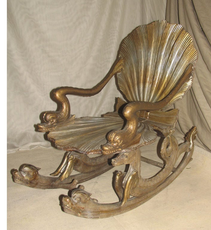 Very Rare handcarved silver gilt grotto rocker.  Stylized shell seat and back with arms in the form of dolphins raised on pair of stylized sea horse rockers atop dolphin head base joined by seaweed carved stretcher.