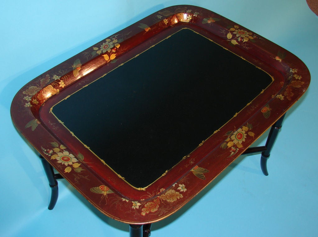 A fine Regency papier mache tray, the burgundy colored border beautifully decorated with exotic gilt flowers and butterflies.  Signed by the maker, now on a stand of a later date.
