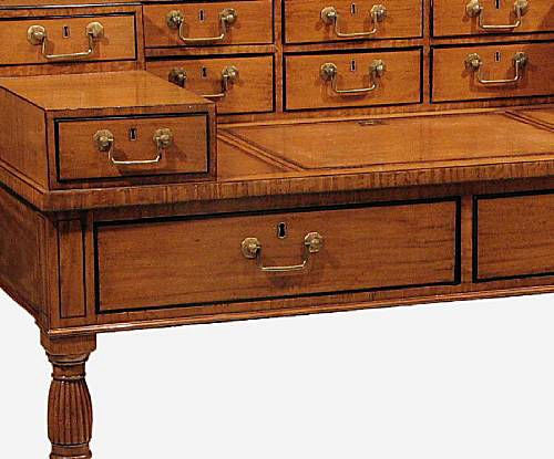 A Regency period satinwood Carlton house writing table, the superstructure with 9 drawers and a brass gallery over 2 long drawers all on reeded and turned legs ending in casters.<br />
Circa 1825.