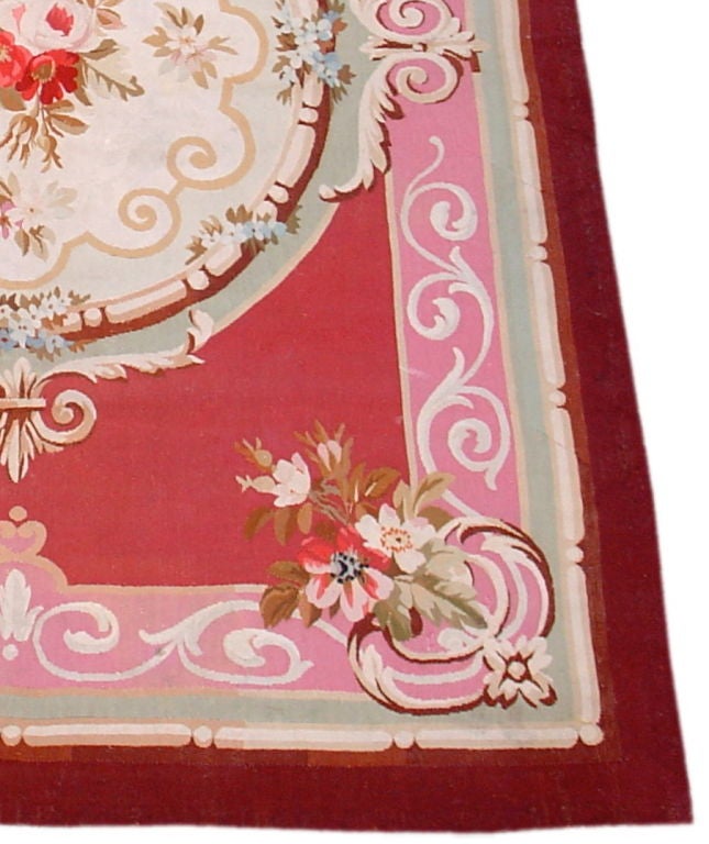 A wonderful scatter-size Aubusson with a cherry red ground and perfect round medallion decorated with scrolls and roses.