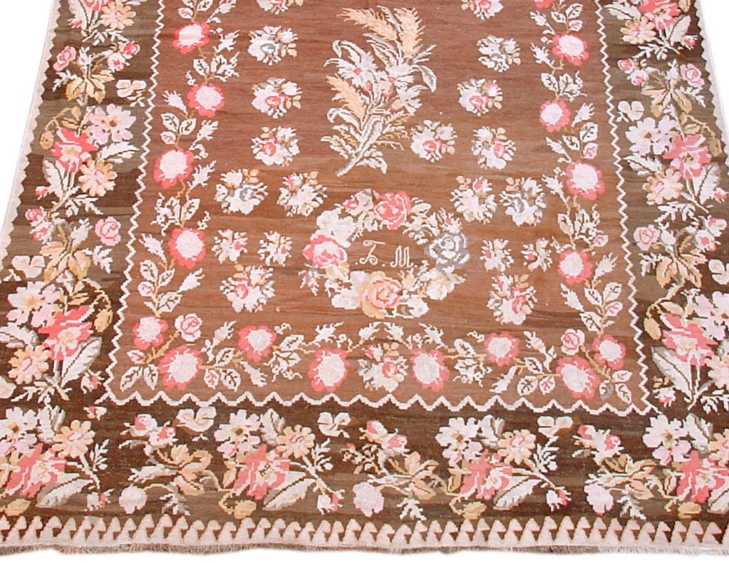 A fascinating decorative flat-weave Kilim in shades of brown, apricot, ivory, grey and gold. Note the prominent woven in date of 1919 in the upper cartouche of roses. Possibly created to be presented as a wedding gift, as the second wreath of roses