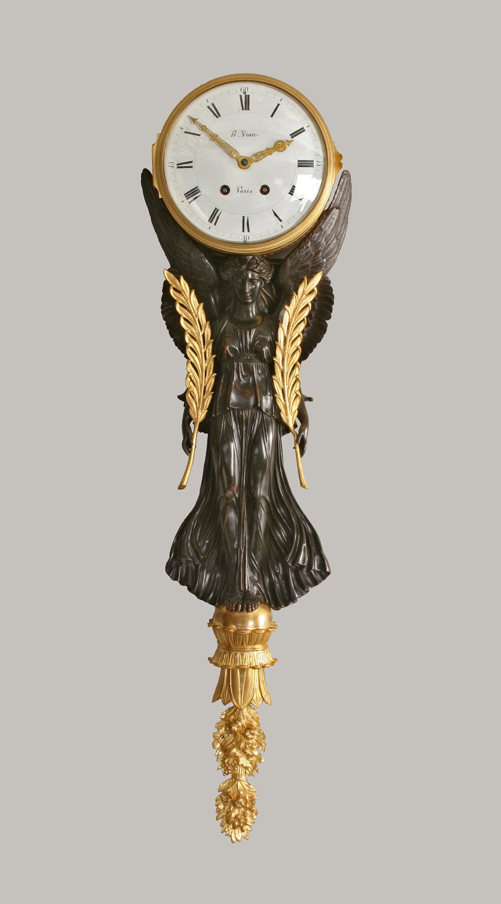 The goddess holding laurel branches and standing on a foliate sphere above a floral bouquet, her outspread wings enveloping the drum case, the enameled clock face fitted with pierced arrow hands.<br />
A similar larger pair of clocks by Thomire et