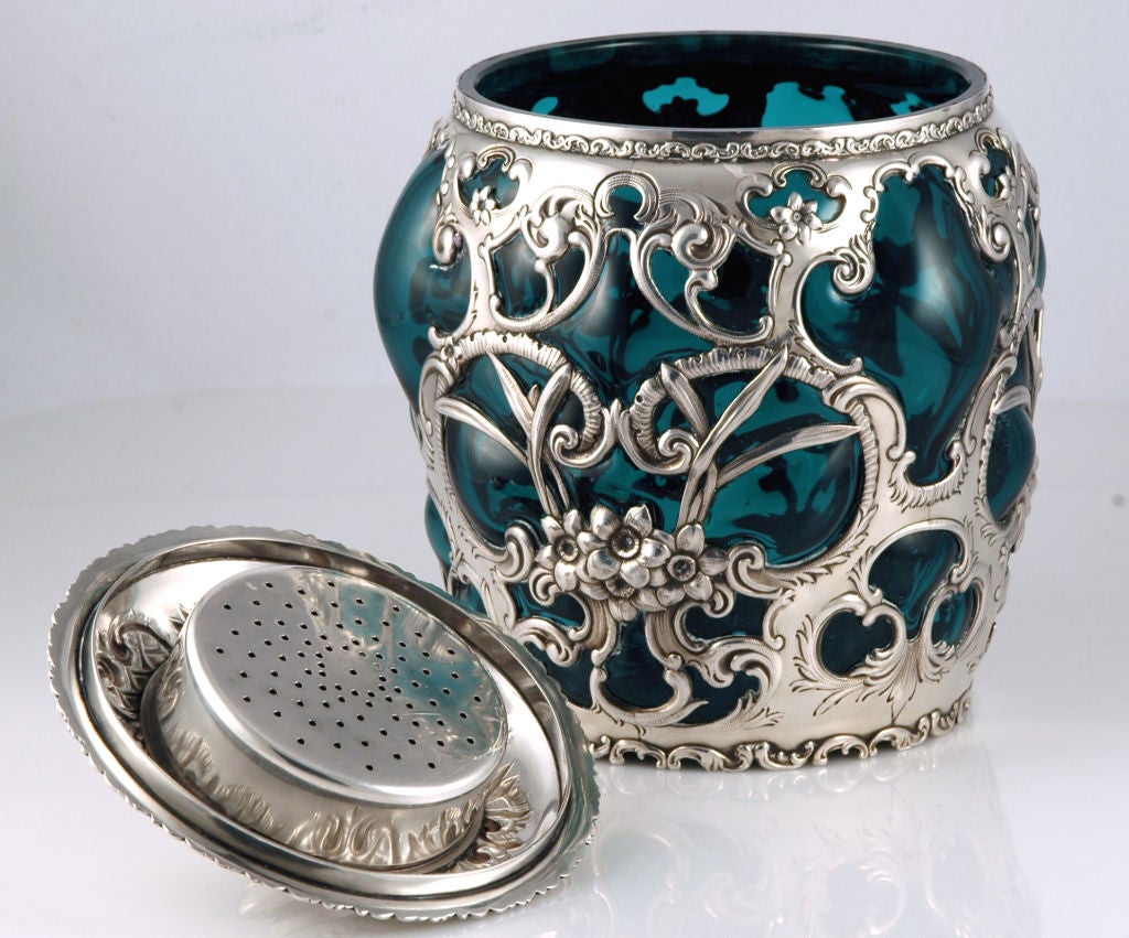PLEASE VISIT LAUREN STANLEY

A fine circa 1899 sterling silver and deep green glass humidor by Whiting, the bulbous shaped lobed glass body overlaid with foliate scrolls, blossoms, strap work, the top with removable pierced component for sponge.