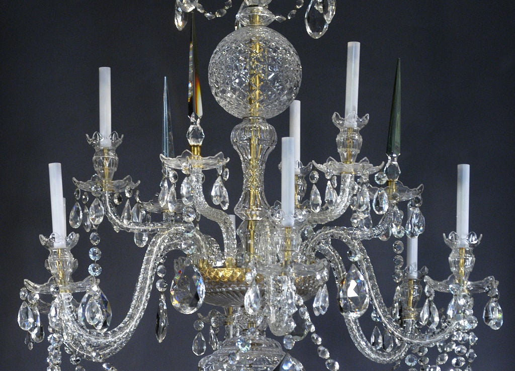 A superb quality Georgian style two-tier 12-arm nine-light, cut crystal chandelier, with a lobed canopy above a ball stem with faceted serpentine arms alternating with spires above a lower canopy, draped with swags of crystal buttons and pendant