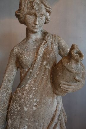 Graceful statue of woman carrying a jug, beautifully worn and softened by weather.
