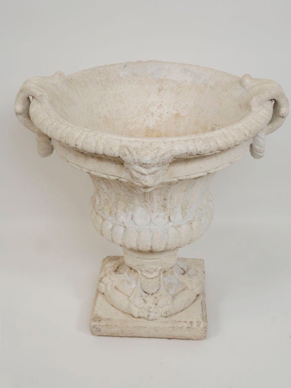 Cast stone pedestal vase features ram's head motif