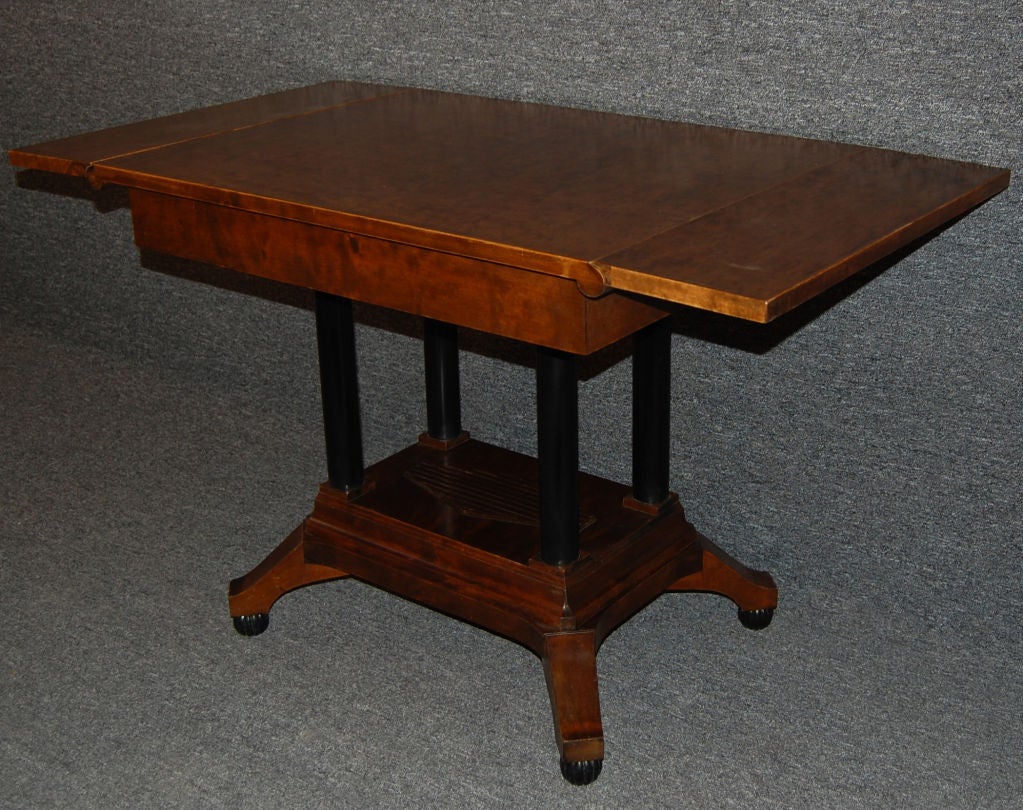 Karl Johan style center table of dark flame birch with ebonized four-column pedestal base from Sweden with drop-leaf table top. The Swedish Karl Johan style is similar to Biedermeier, which emphasizes clean lines and minimal ornamentation. It is