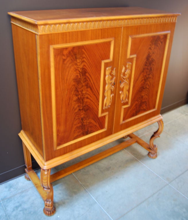 Swedish Neoclassical Credenza Cabinet of golden elm and crotch mahogany designed by Otto Schulz for Boet. Armoire features beautiful carved doors and legs. This stunning storage piece has five adjustable shelves and three drawers. Could also work