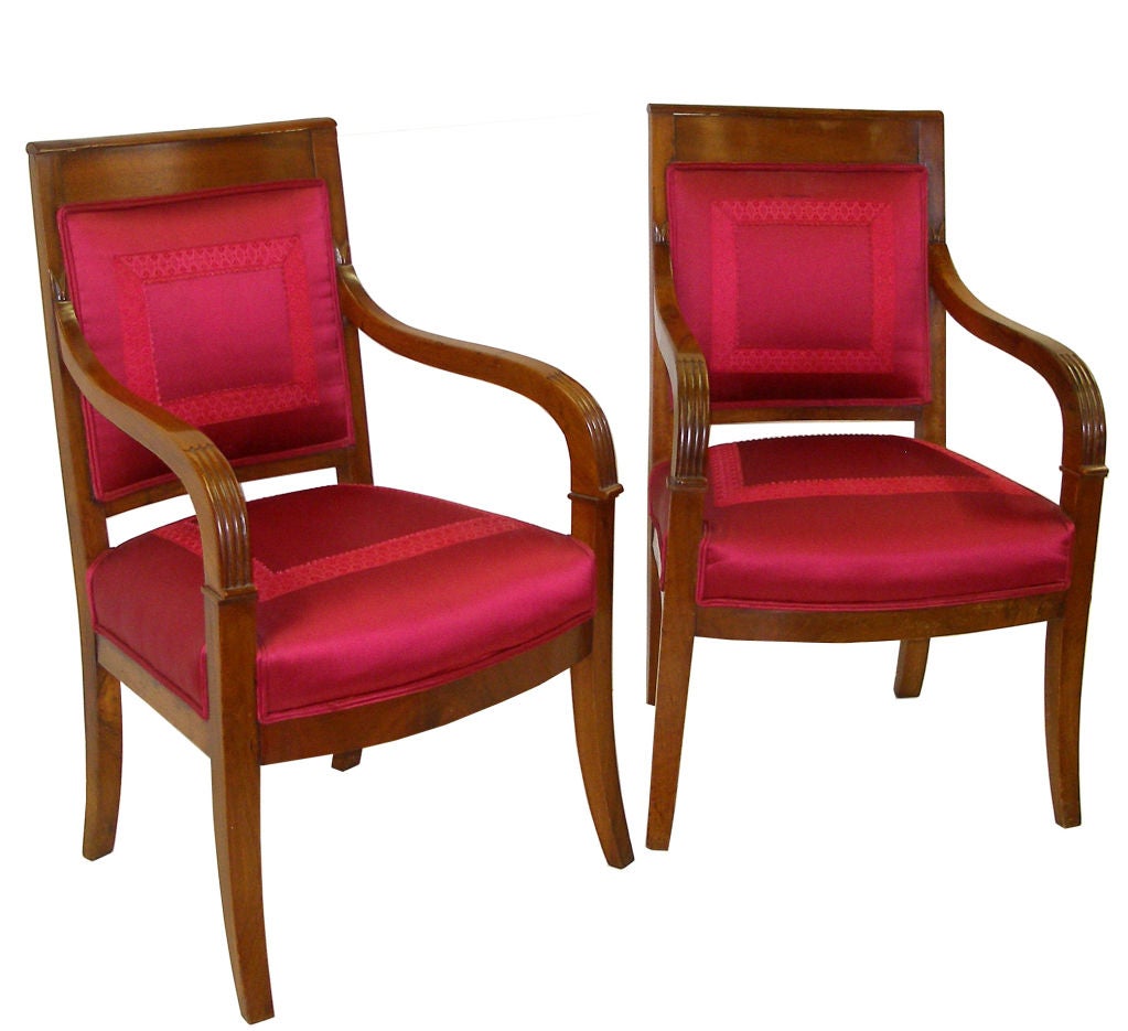 Pair of Empire mahogany open arm chairs with red upholstery.  Having reed form front arms with sabre legs.