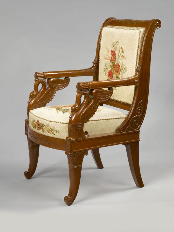A beautiful set of four French Empire period, mahogany and mahogany veneer fauteuils with inverted backs that have carved decoration of roses and palms.  The arms rest on carved winged swan necks.  The arched feet are carved with lotus leaves.  The