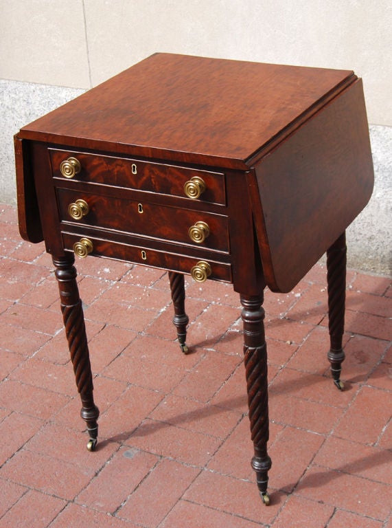 Mahogany drop-leaf work table with turned legs and castors, and brass knobs. A wonderful painted late 19th century gameboard was fit into the bottom drawer.