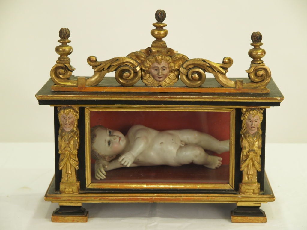 Beautifully carved, detailed Reliquary containing a smiling Baby Jesus. Quality of the cabinet is superb despite its age and gilt painted wood is still in remarkable condition.

Baby Jesus, thought to be made of clay or papier mache, painted and
