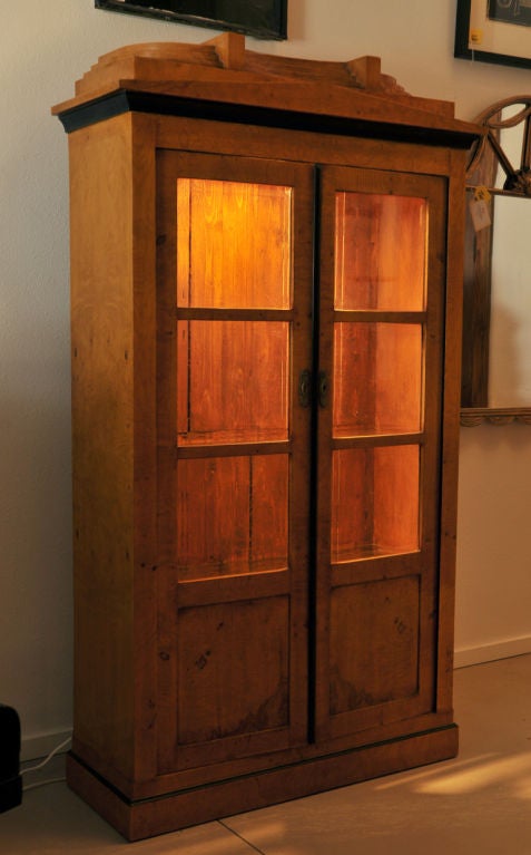 Biedermeier Cabinet circa late 1800's with beveled glass mullion doors, beautiful  chestnut burl wood and ebonized accents along with a molded base. Recently added  glass shelves (three) with a single puck light on the inside top, perfectly