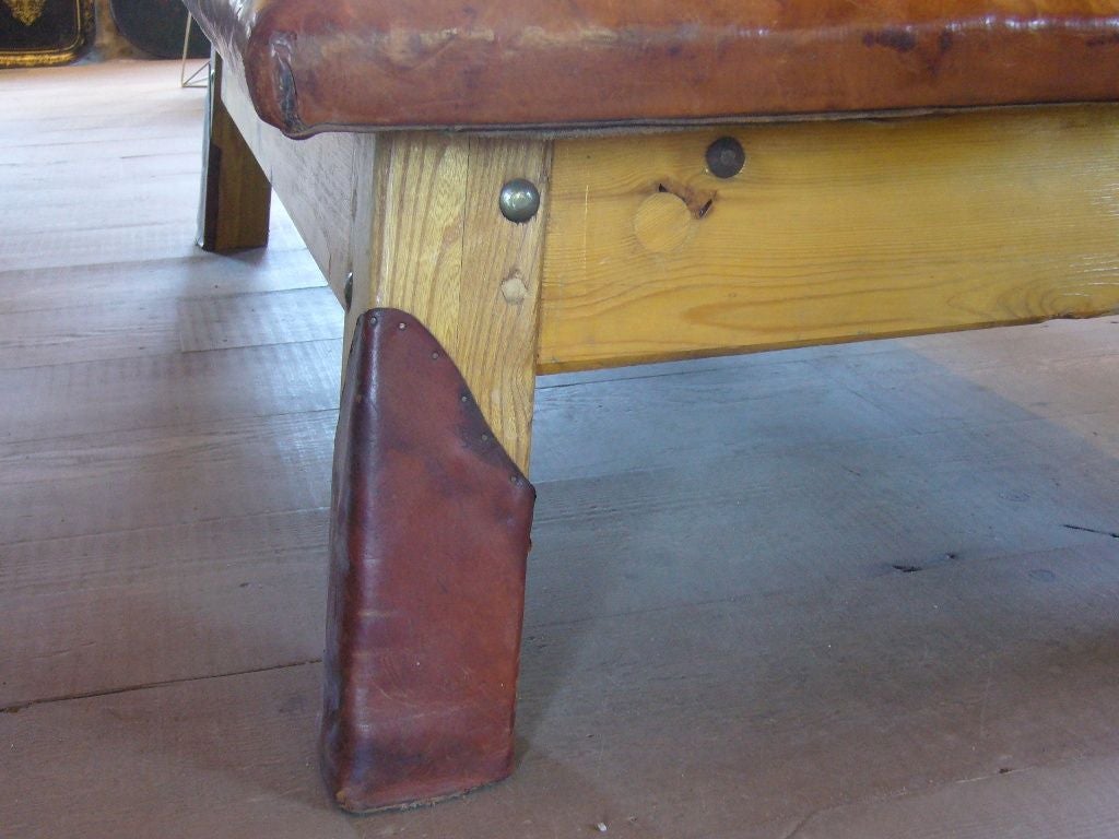 Vintage leather massage table, also used as a gymnasts bench.  The leather bench has wooden legs as well as a set of four metal legs that can be attached to add height to the bench.<br />
(Each bench sold seperately)