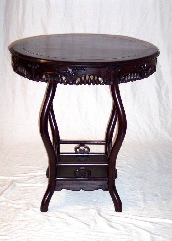 Elegant round tea table constructed of rare Blackwood, with carved details and sinuous legs.  Removable top attaches and detaches via wood pins (see photo of underside).