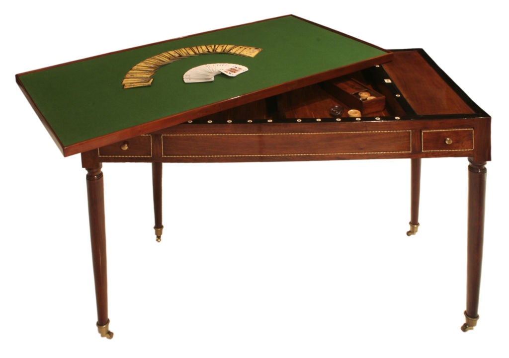 This fine mahogany table features a reversible top; one side with an elegant green leather inset, for use as a writing desk, the other with green felt for card playing. Removing the tabletop reveals a backgammon board. Two drawers on opposite sides