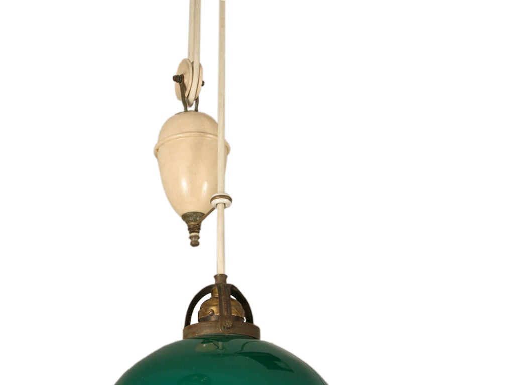 Hanging light with agreen glass shade on an adjustable canvas wrapped cord with counter weight.