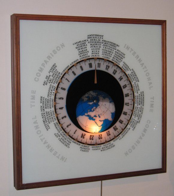 A Wall Clock, showing the time zones in certain countries and cities. Consisting of two glass plates, one fixed and the other revolving displaying both the time and the suns position.