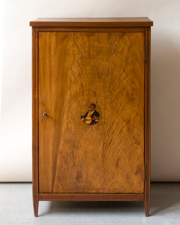 A Directoire style walnut single door low cabinet with line inlay in the door frame, with a center marquetry medallion of a finely dressed smiling banjo player, as is, (with restorations.)

Measure: Width 22½