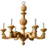 A carved light wood 6 arm chandelier decorated with masks of men A carved light wood 6 arm chandelier decorated with masks of men