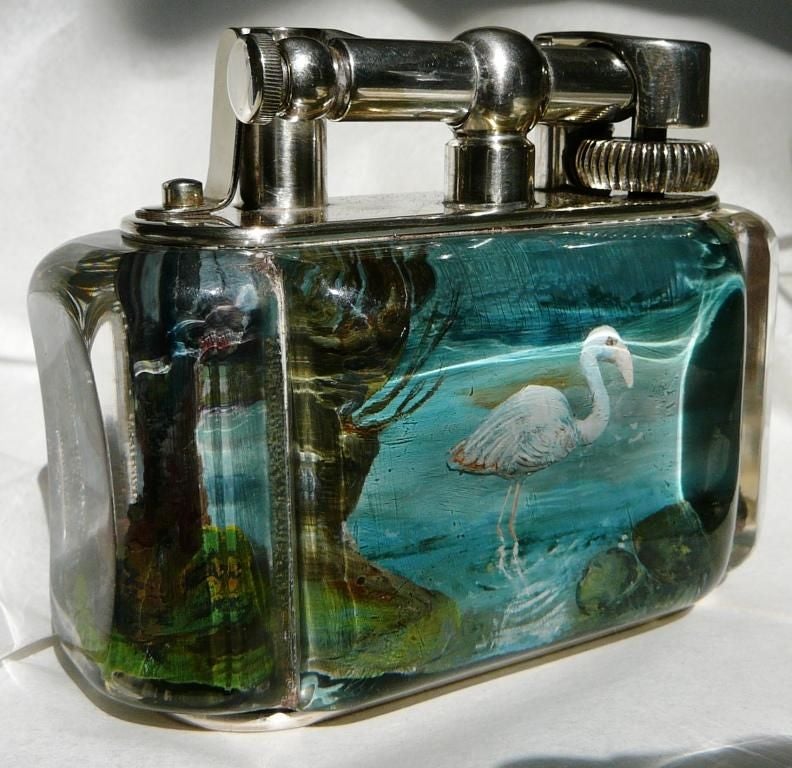 A very rare silver-plated 'Aquarium' table lighter in ‘Half-Giant’ size, the perspex body enclosing intaglio decoration of pink and pale blue flamingos in a continuous watery landscape, with silver plated lift-arm marked DUNHILL, the reservoir cover