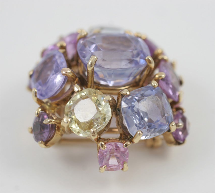 elegant sapphire cluster brooch pastel blue pink and yellow sapphires<br />
center blue sapphire 10 carats<br />
7 blue pink, yellow and purple sapphires 23 carats<br />
7 pink and purple sapphires  5 carats