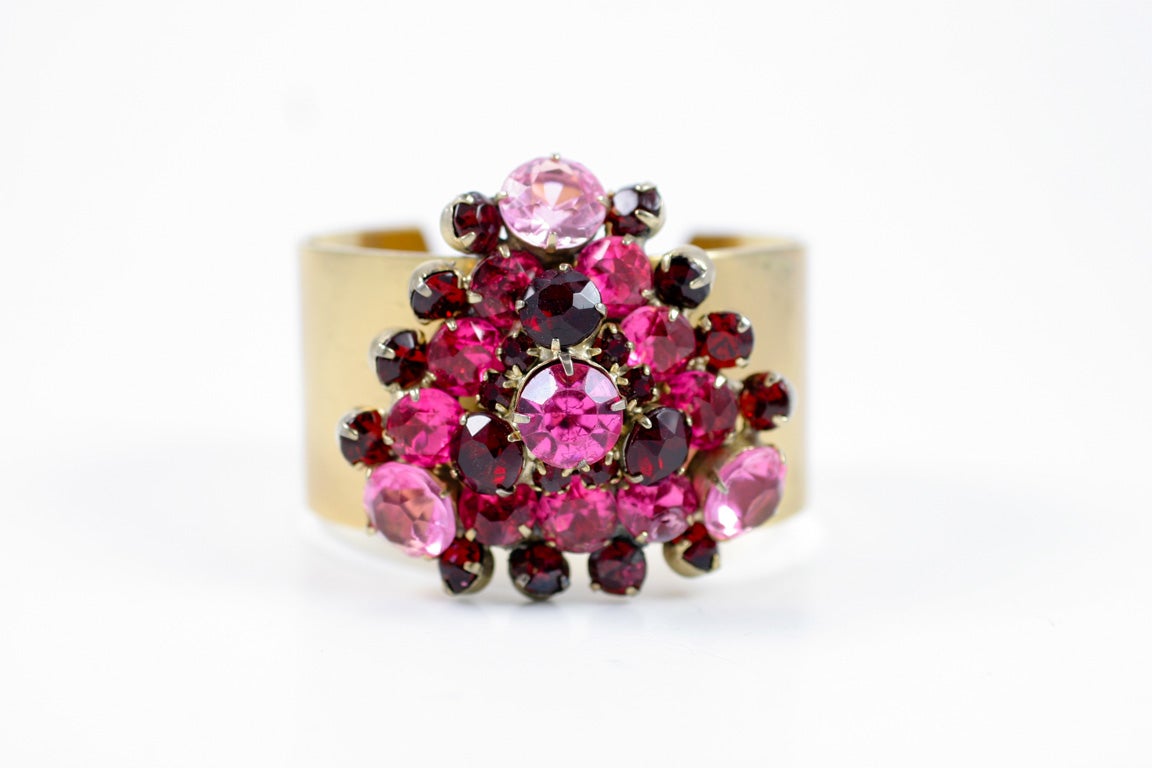 Vendome gold tone wide band cuff bracelet with a large cluster of brilliant cut red and pink prong set rhinestones.