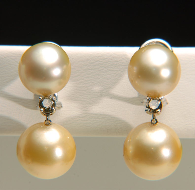 18k White Gold Earrings each with two Golden South Sea Pearls. Natural Color. (Top Pearl 11.5mm bottom 13mm) with a Fancy Brown Diamond prong set between. Dia Wt=0.50cts. Marked (750,18k,MC)