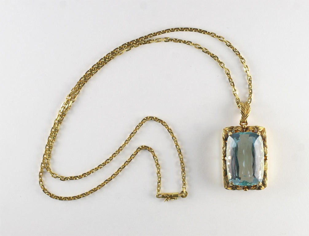 Magnificent faceted Aquamarine  set in 18kt Yellow Gold Leaf like Oblong Pendant with associated chain.  Aqua is prong set and mounted on engraved leaf-like mounting, which has a raised gallery.  Approximately 35-40 cts.  Great intense color.