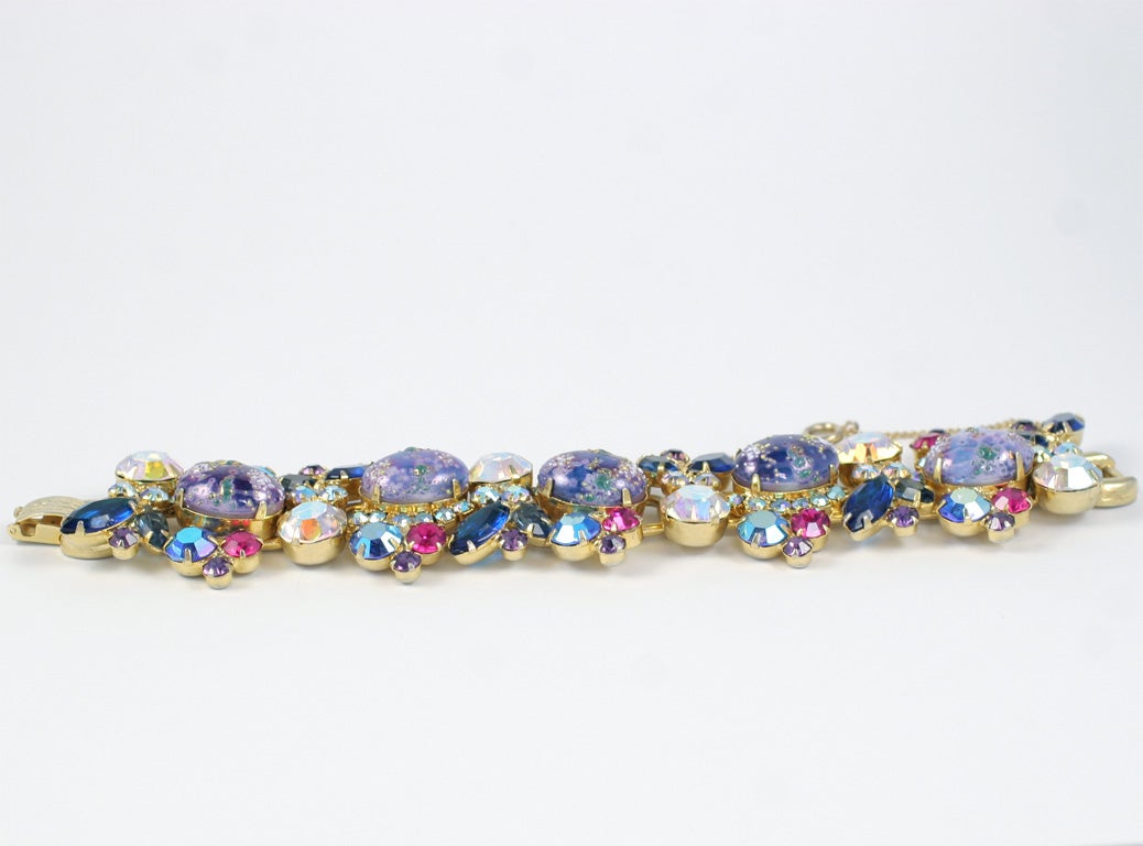 Spectacular bracelet with hot pink, navy blue, lavender, and aurora borealis rhinestones and mottled oval lavender cabochons. Has a safety chain.